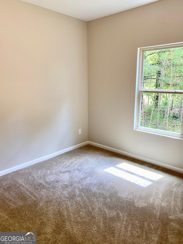 spare room featuring carpet and baseboards