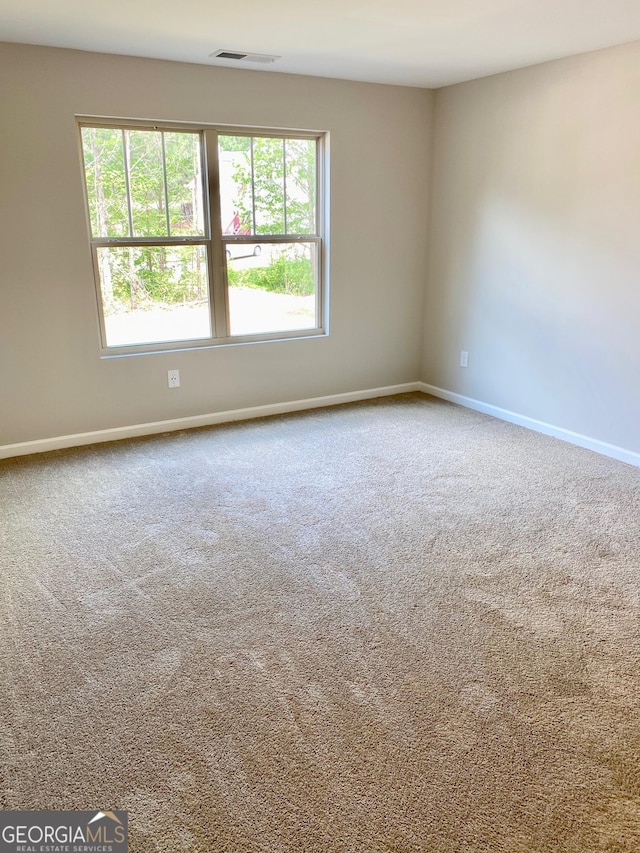 spare room featuring baseboards, visible vents, and carpet flooring