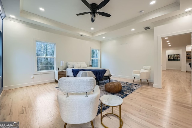 bedroom featuring a tray ceiling, ceiling fan, and light wood-type flooring