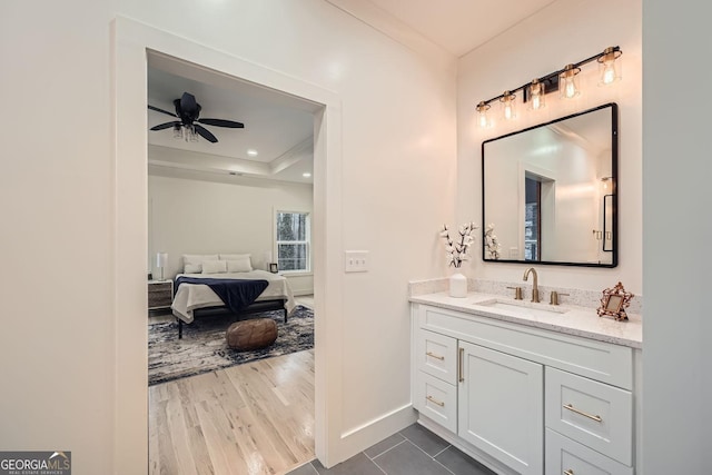 bathroom featuring vanity, wood-type flooring, ceiling fan, and a tray ceiling