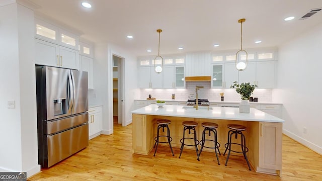 kitchen featuring white cabinetry, stainless steel fridge with ice dispenser, and an island with sink