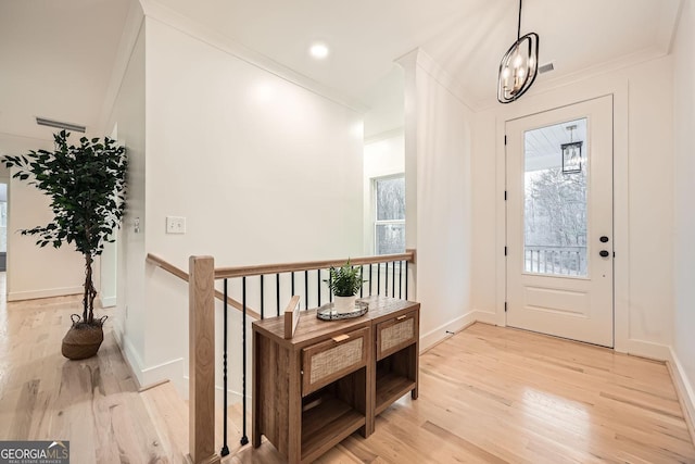 foyer featuring ornamental molding, a notable chandelier, and light hardwood / wood-style floors