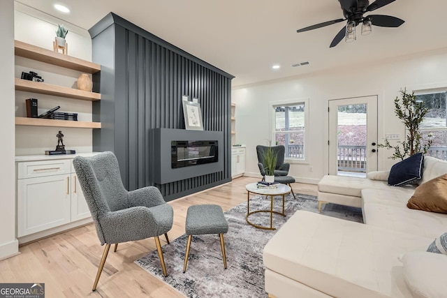 living room featuring crown molding, ceiling fan, and light wood-type flooring