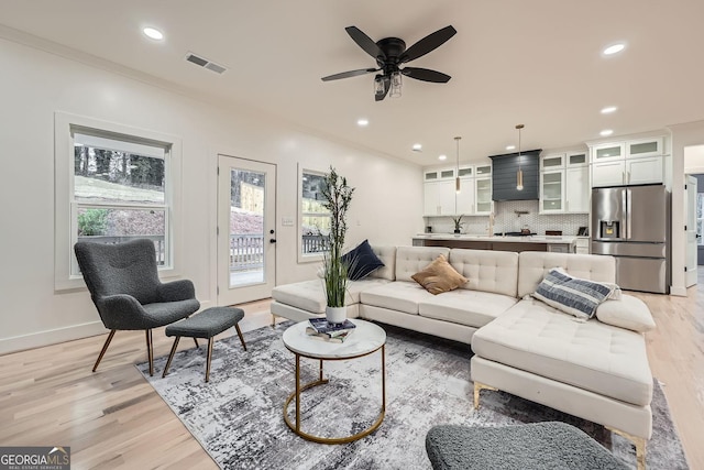 living room featuring crown molding, a wealth of natural light, and light wood-type flooring