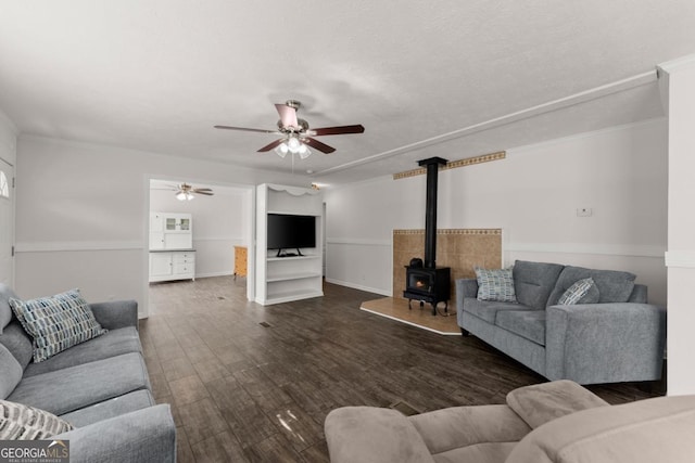 living room with dark hardwood / wood-style flooring, ceiling fan, and a wood stove