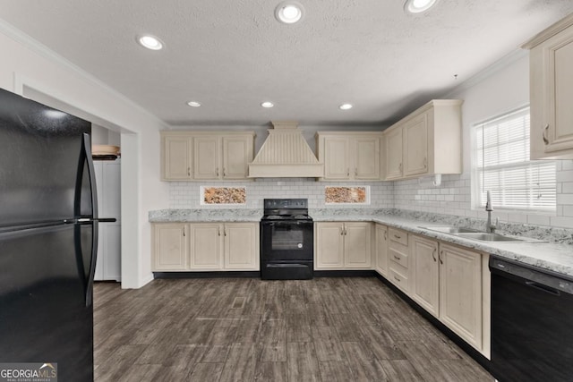 kitchen featuring black appliances, premium range hood, dark hardwood / wood-style flooring, sink, and cream cabinets