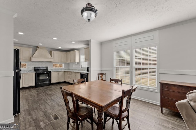 dining space with sink, a textured ceiling, crown molding, and dark wood-type flooring