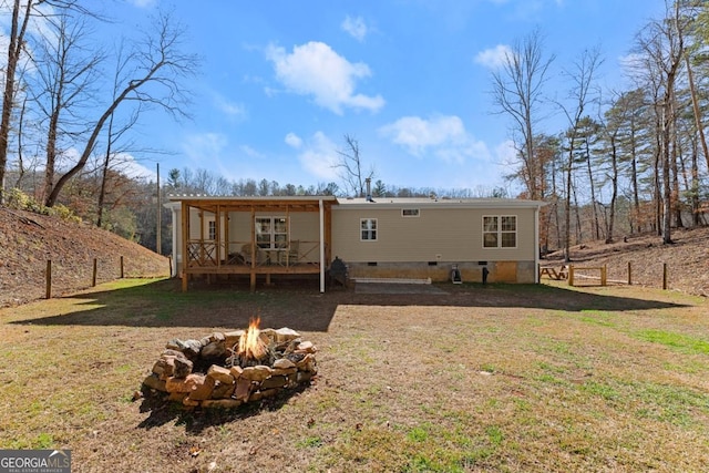 rear view of house featuring a lawn and a fire pit