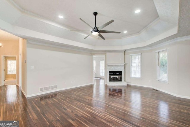 unfurnished living room featuring crown molding, dark wood-type flooring, and a tray ceiling