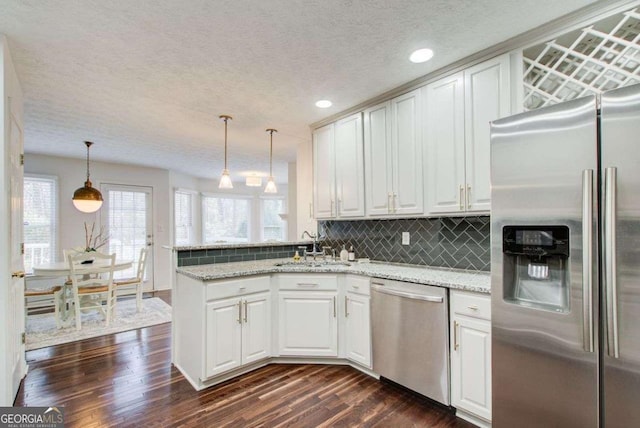 kitchen featuring white cabinetry, dark hardwood / wood-style floors, pendant lighting, decorative backsplash, and appliances with stainless steel finishes