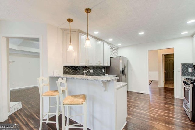 kitchen featuring backsplash, light stone countertops, a breakfast bar, and hanging light fixtures