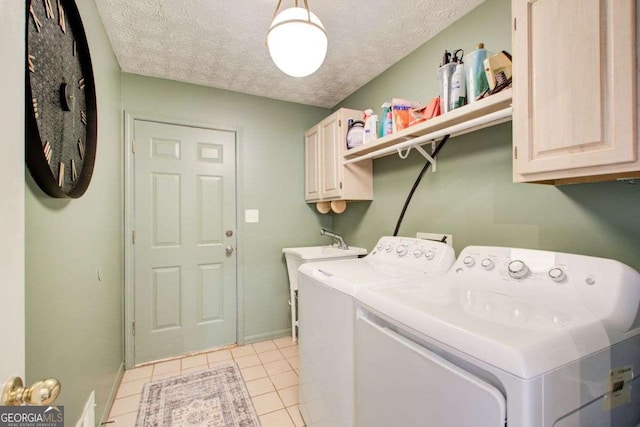 clothes washing area with washing machine and dryer, light tile patterned floors, cabinets, and a textured ceiling