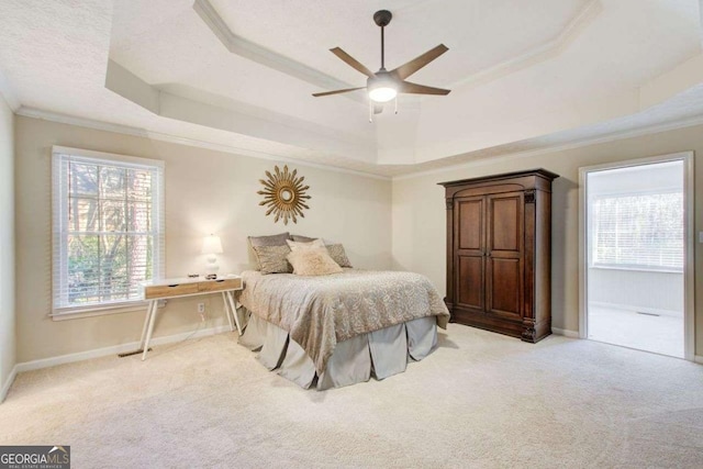 bedroom with ceiling fan, light colored carpet, ornamental molding, and a tray ceiling