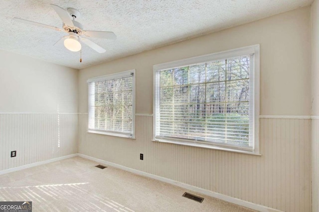 spare room with a textured ceiling, carpet floors, and ceiling fan