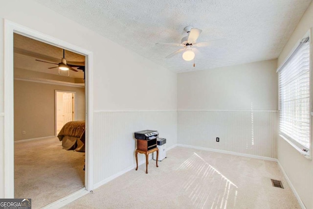 carpeted spare room featuring a textured ceiling and ceiling fan