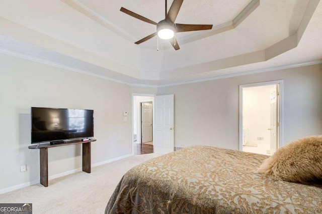 bedroom featuring a raised ceiling, connected bathroom, ceiling fan, and ornamental molding