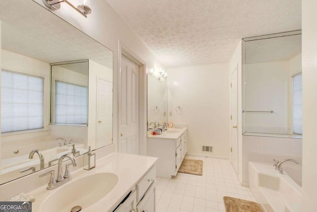 bathroom with a textured ceiling, vanity, a bath, and tile patterned floors