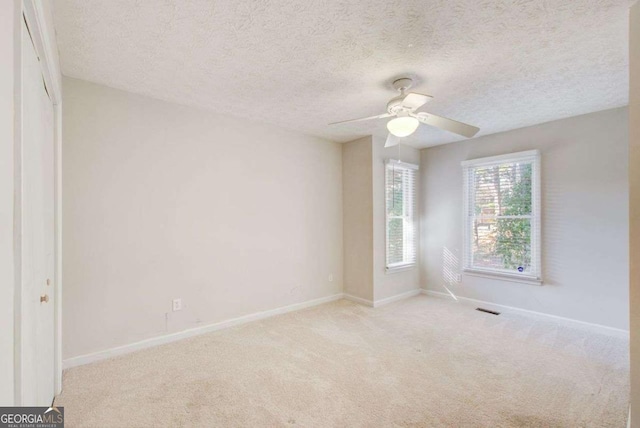 unfurnished room featuring ceiling fan, light colored carpet, and a textured ceiling