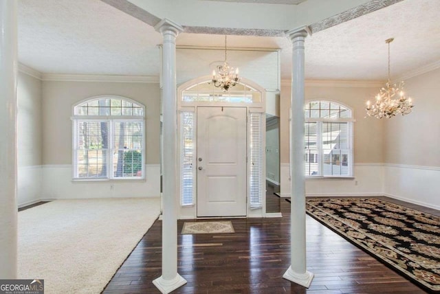 foyer entrance featuring ornate columns, ornamental molding, and a chandelier