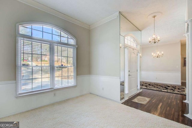 foyer with crown molding and a chandelier