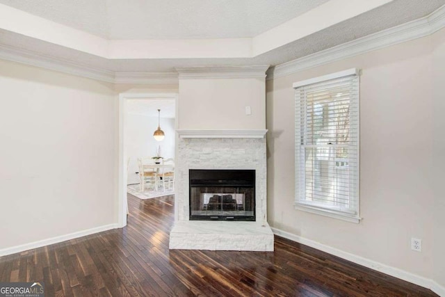 unfurnished living room featuring dark hardwood / wood-style flooring, a raised ceiling, ornamental molding, and a fireplace