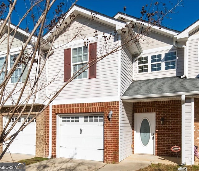 view of front of property with concrete driveway, brick siding, an attached garage, and roof with shingles