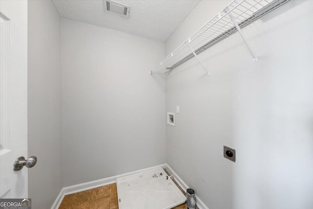 washroom with visible vents, hookup for an electric dryer, a textured ceiling, laundry area, and baseboards