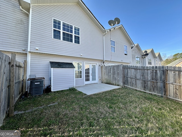 back of property with central AC unit, a lawn, a fenced backyard, french doors, and a patio area