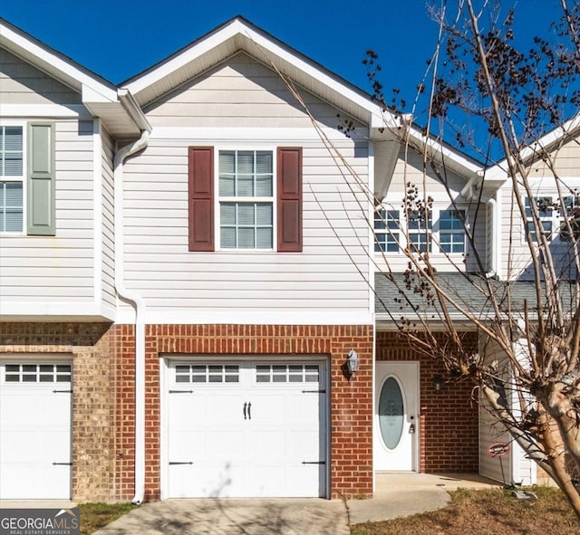 view of property featuring a garage, concrete driveway, and brick siding