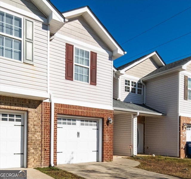 view of front of property featuring an attached garage, driveway, and brick siding