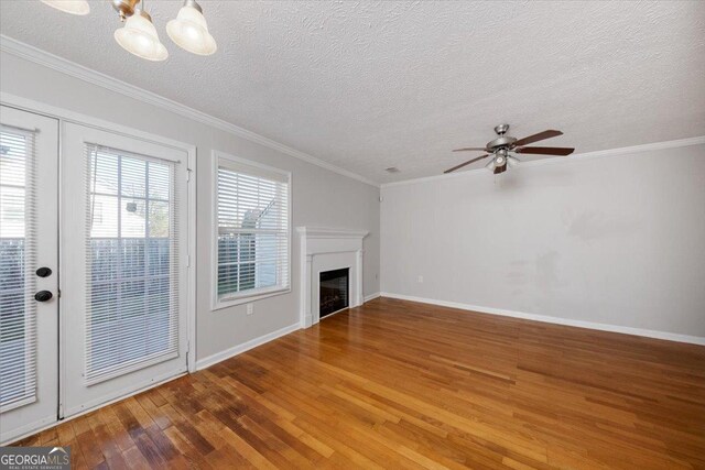 unfurnished living room featuring hardwood / wood-style floors, ceiling fan with notable chandelier, crown molding, and a textured ceiling