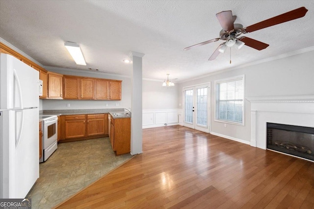 kitchen with brown cabinets, light countertops, open floor plan, a sink, and white appliances