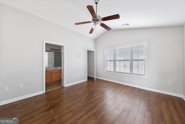 unfurnished bedroom with dark wood-style floors, lofted ceiling, visible vents, and baseboards