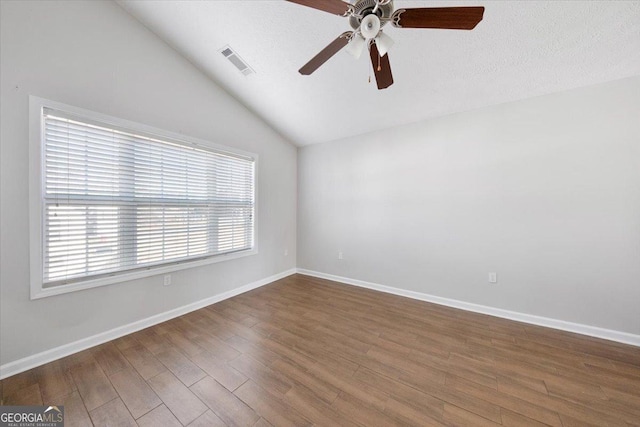 unfurnished room with visible vents, vaulted ceiling, a textured ceiling, wood finished floors, and baseboards