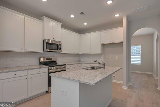 kitchen with white cabinetry, sink, hanging light fixtures, a kitchen island with sink, and stainless steel appliances