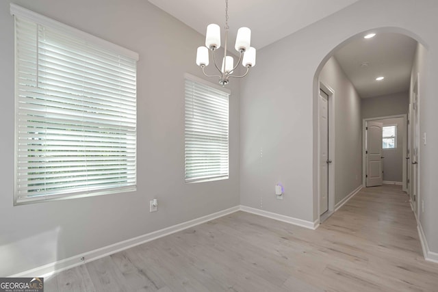 unfurnished dining area with a notable chandelier and light wood-type flooring