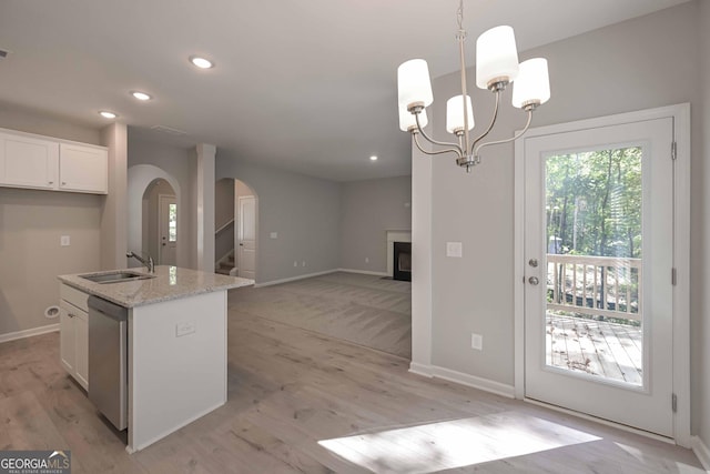 kitchen featuring sink, a center island with sink, dishwasher, light stone countertops, and white cabinets