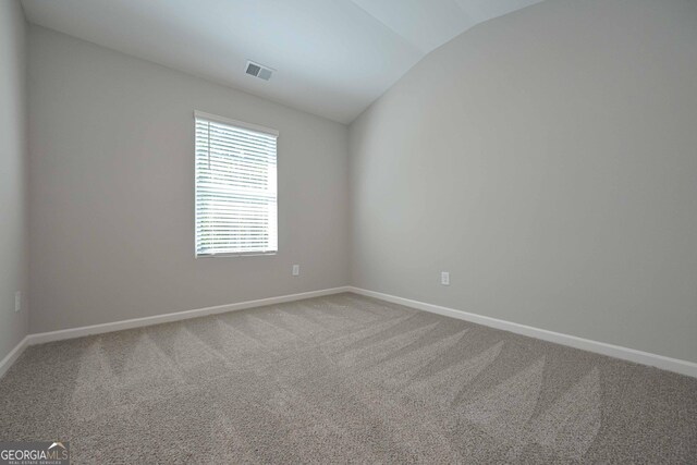 carpeted empty room featuring vaulted ceiling