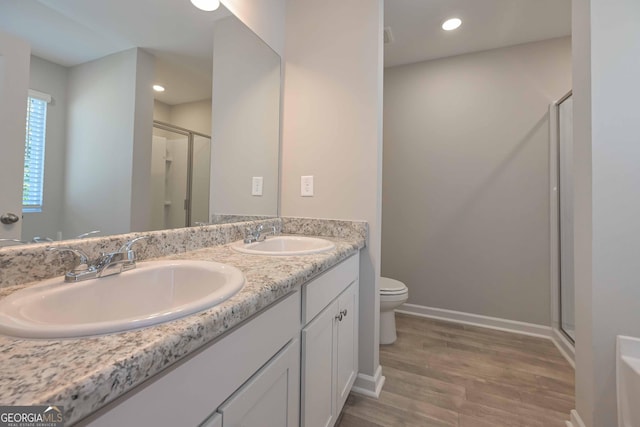 bathroom with vanity, hardwood / wood-style floors, a shower with door, and toilet