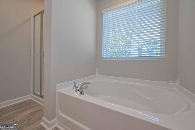 bathroom with wood-type flooring and independent shower and bath