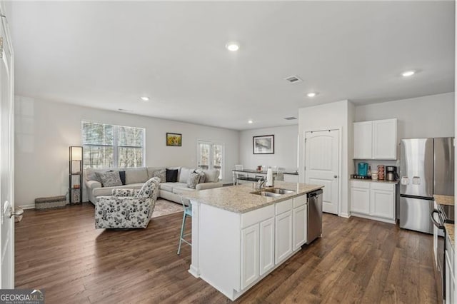 kitchen with stainless steel appliances, sink, white cabinetry, an island with sink, and dark hardwood / wood-style flooring