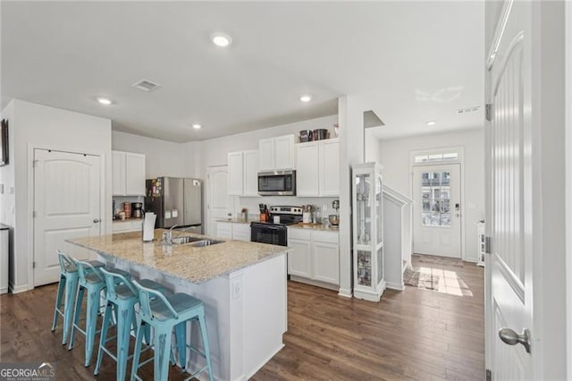 kitchen featuring stainless steel appliances, an island with sink, light stone counters, white cabinets, and sink