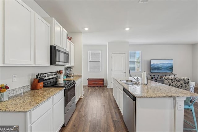 kitchen featuring stainless steel appliances, an island with sink, a kitchen bar, sink, and white cabinetry