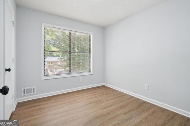 unfurnished room with light hardwood / wood-style flooring and a textured ceiling