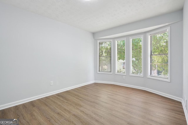 unfurnished room featuring a textured ceiling and light wood-type flooring