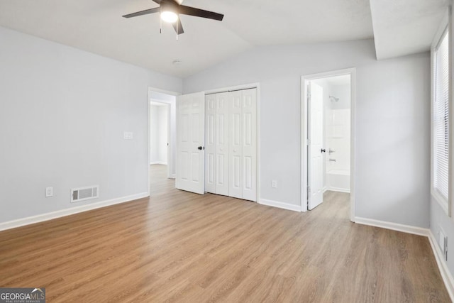 unfurnished bedroom featuring connected bathroom, ceiling fan, light hardwood / wood-style floors, and vaulted ceiling