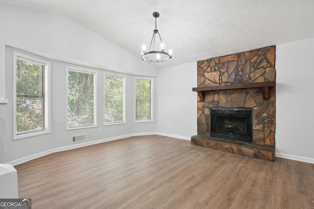 unfurnished living room featuring a healthy amount of sunlight, an inviting chandelier, a fireplace, and vaulted ceiling