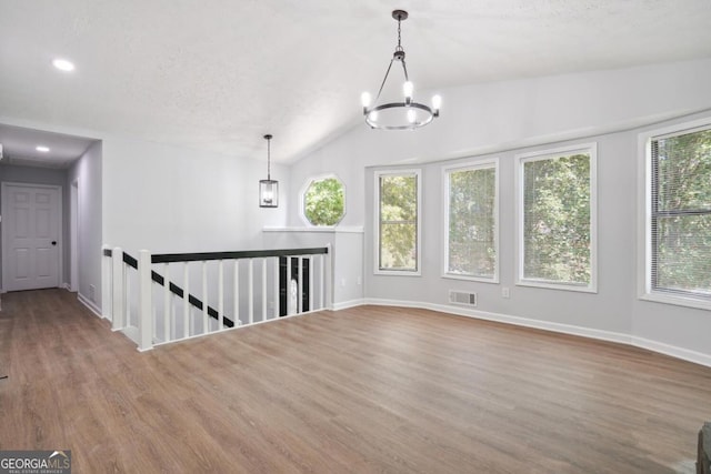 unfurnished room featuring a healthy amount of sunlight, vaulted ceiling, and an inviting chandelier