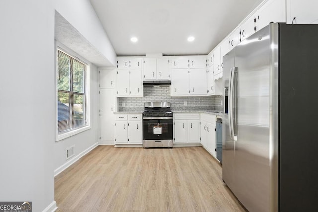 kitchen with light hardwood / wood-style floors, white cabinetry, stainless steel appliances, and tasteful backsplash