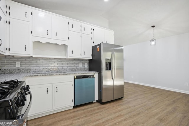 kitchen with white cabinets, vaulted ceiling, appliances with stainless steel finishes, tasteful backsplash, and decorative light fixtures